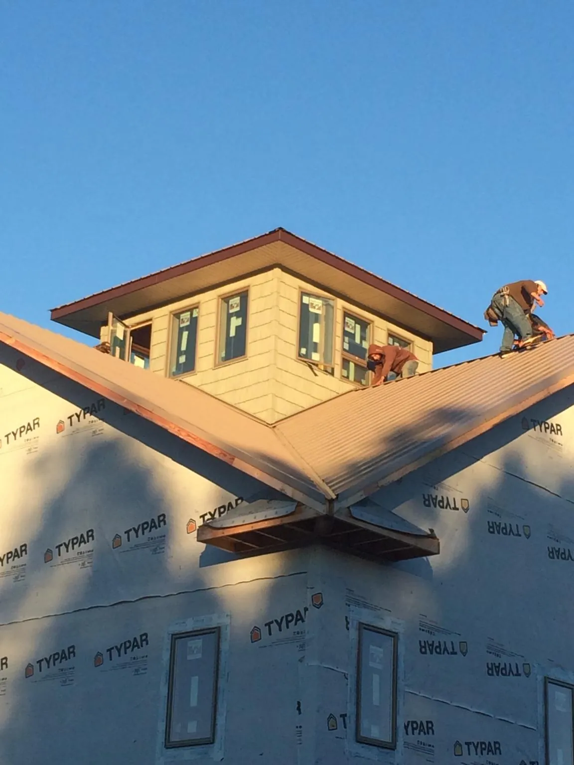 Roofers working around a rooftop cupola on a new metal roof at sunset — Roof Waterproofing in Reedsville by Roofing Brothers